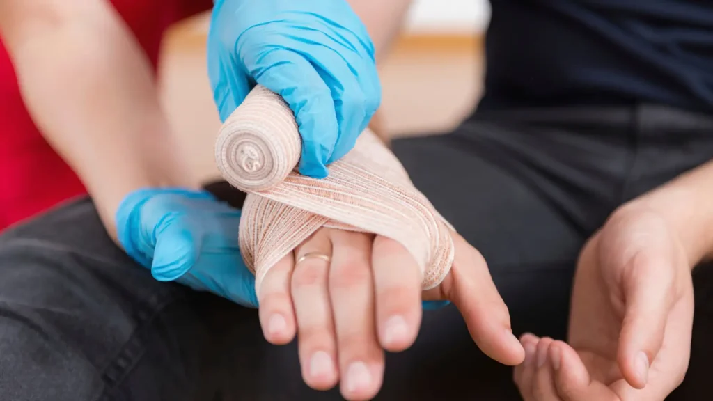 Medical professional wrapping a bandage around an injured hand.