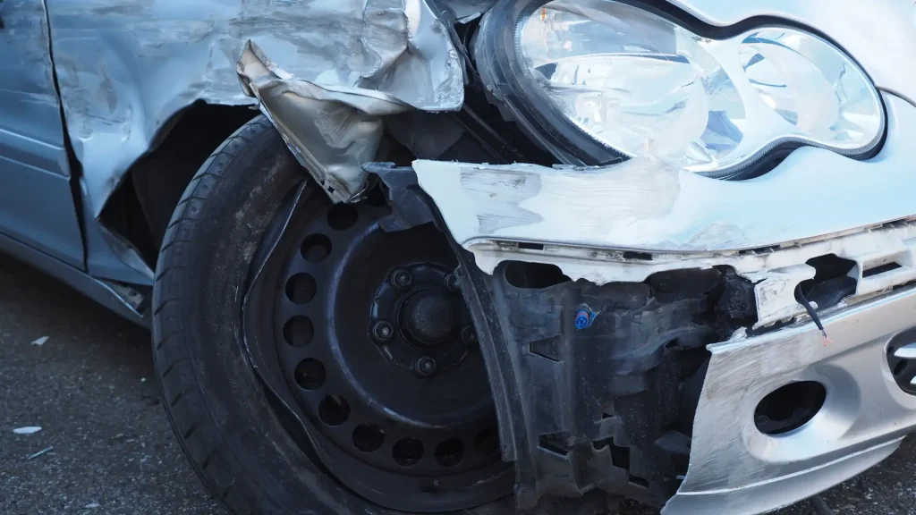 Close-up of a damaged car wheel and body, showing significant impact on the fender and tire