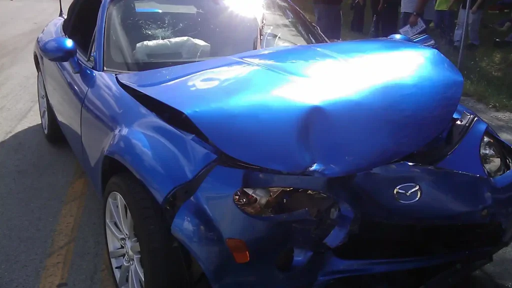 A severely damaged blue car with a crushed front end after a collision