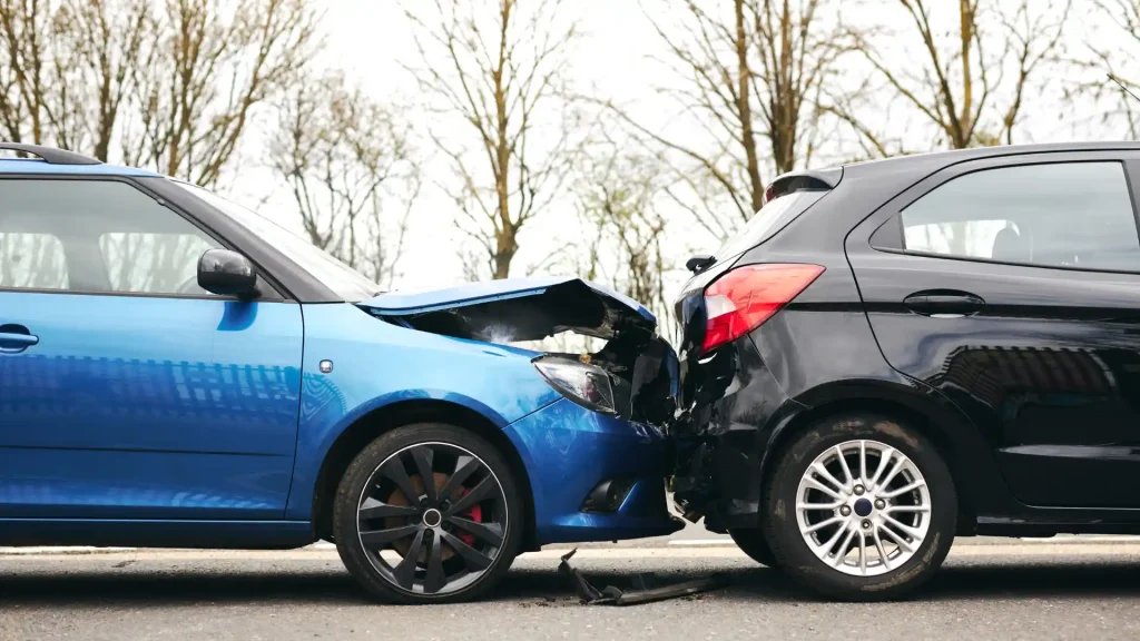 A blue car rear-ended by a black car, showing visible damage.