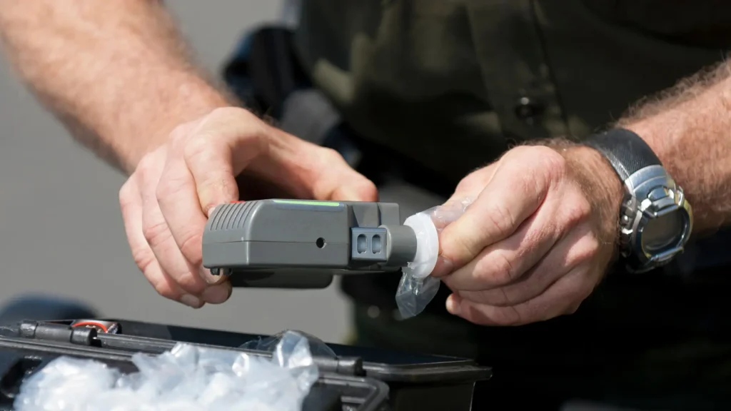 Police officer holding a breathalyzer device