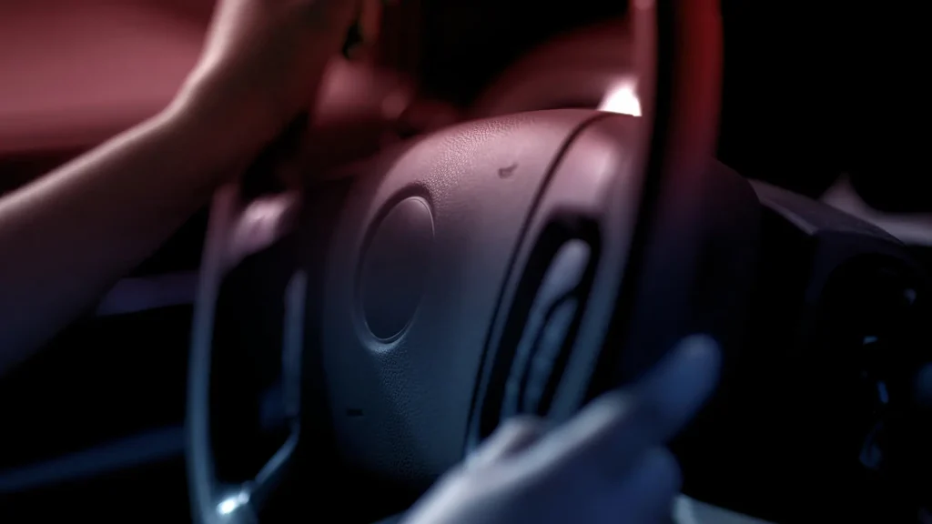 Close-up of driver’s hand on steering wheel with police lights