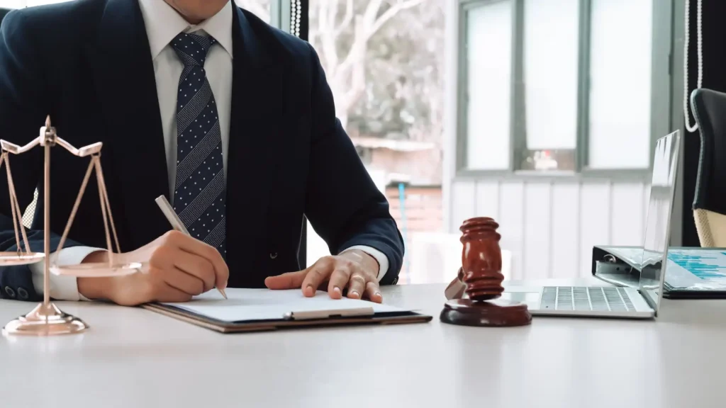 A lawyer signing documents with a gavel on the table