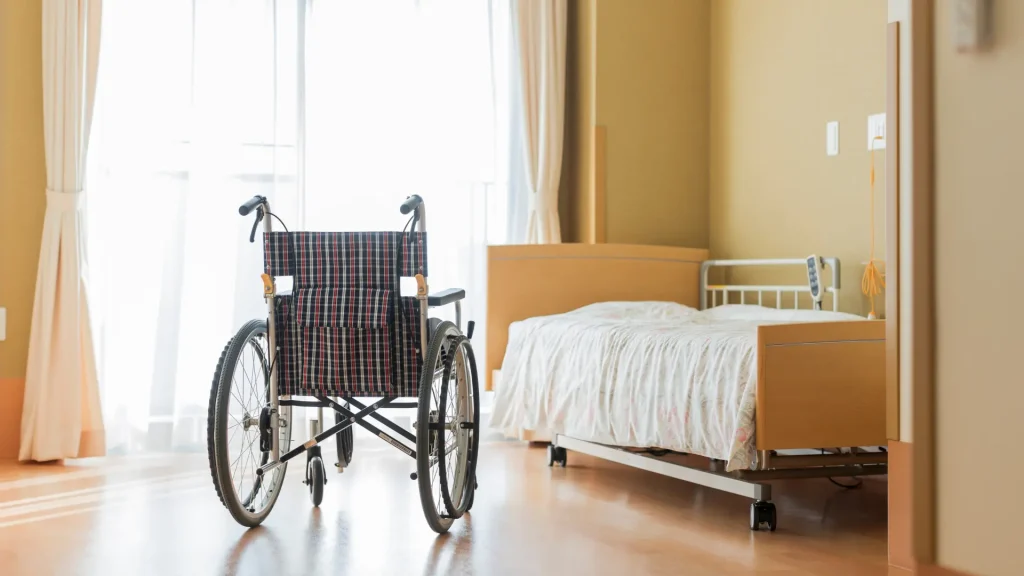Wheelchair placed next to an empty bed in a hospital room.