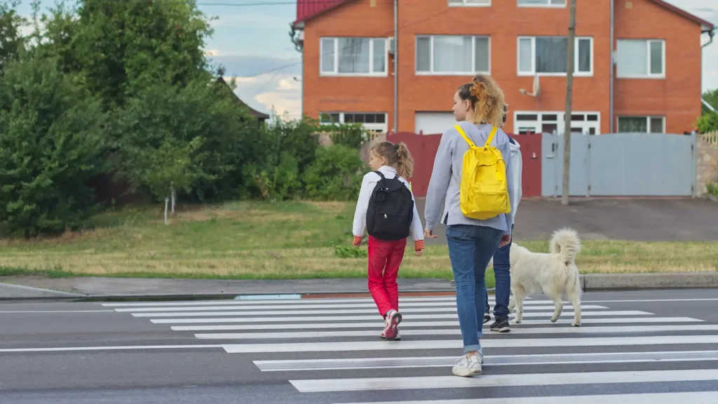 Mother and child walking across a crosswalk with a dog