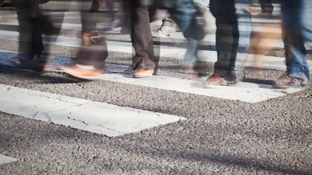 Close-up of people's feet crossing a pedestrian crosswalk