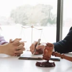 Gavel and scales on table as lawyer drafts paperwork