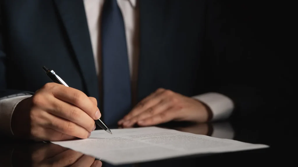 Attorney signs legal document on reflective desk