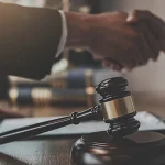 Gavel in focus as attorney and client shake hands