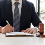 Lawyer writes on clipboard with gavel nearby