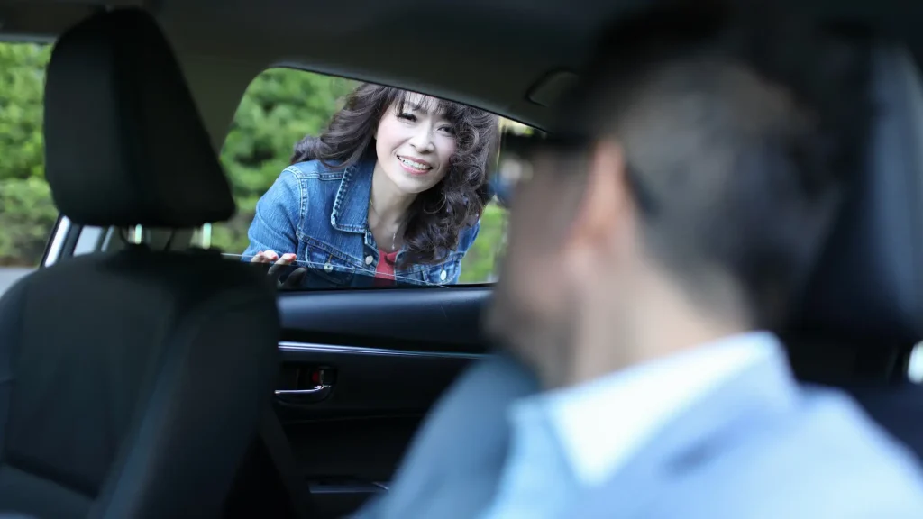 Woman looking into a car window with a man inside.