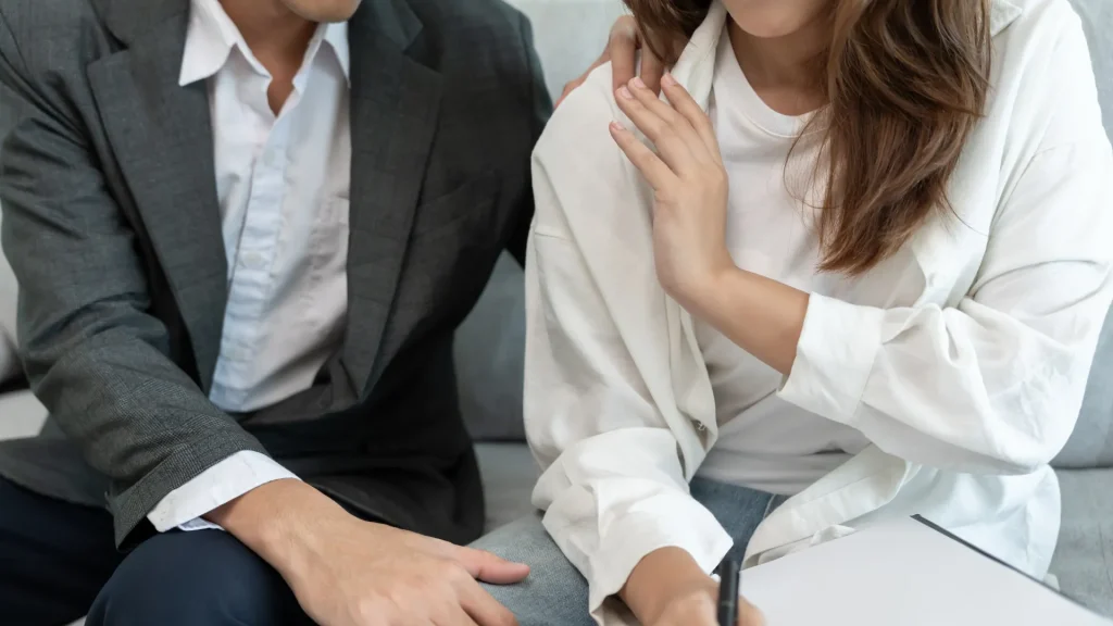 Woman pushing away coworker’s hand on her shoulder