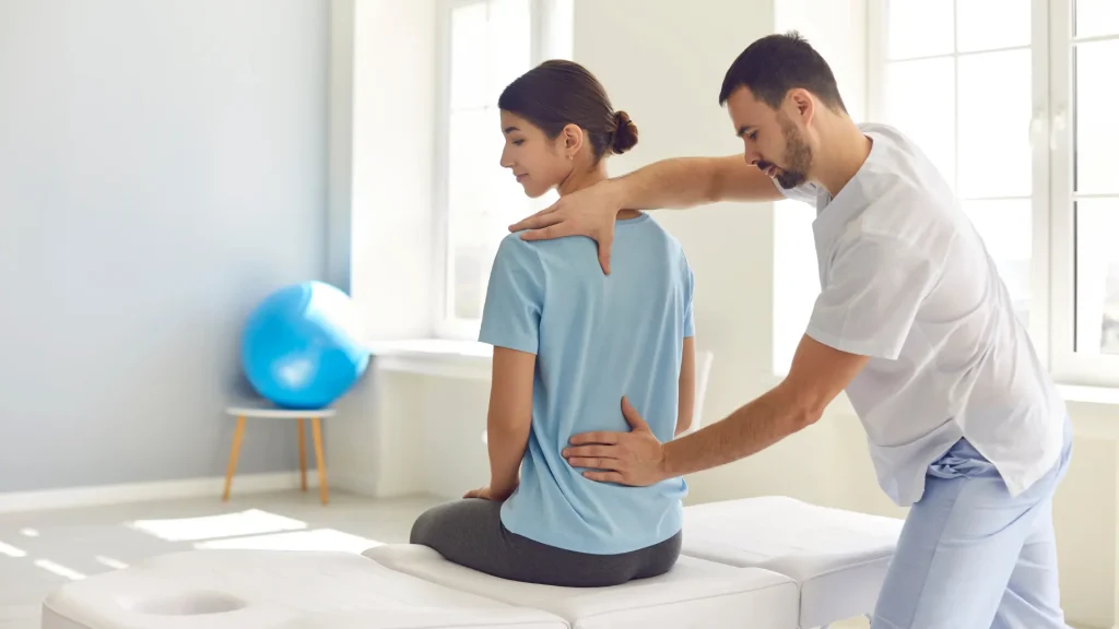 Physical therapist examining a woman's back during a session.