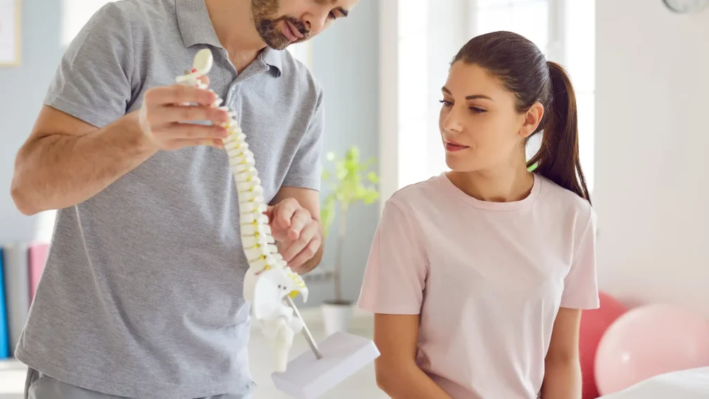 Doctor showing spine model to patient during consultation.