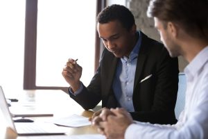 Person looking down at a desk prepared to sign papers while sitting next to someone.