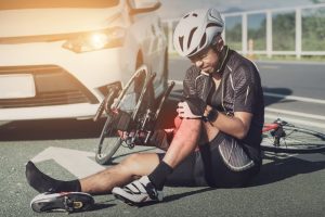 Bicycler holding leg after accident.