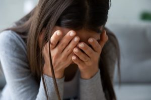 Woman in grey shirt with head in hands