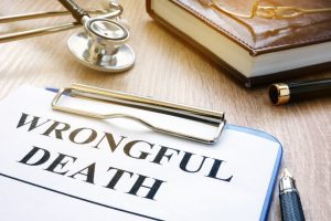 Clipboard with wrongful death written on it on desk next to stethoscope and books.